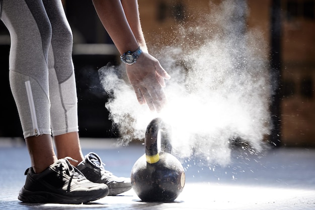 Femme poudre mains kettlebell fitness et prêt pour l'entraînement de gym et l'exercice dans un club sain