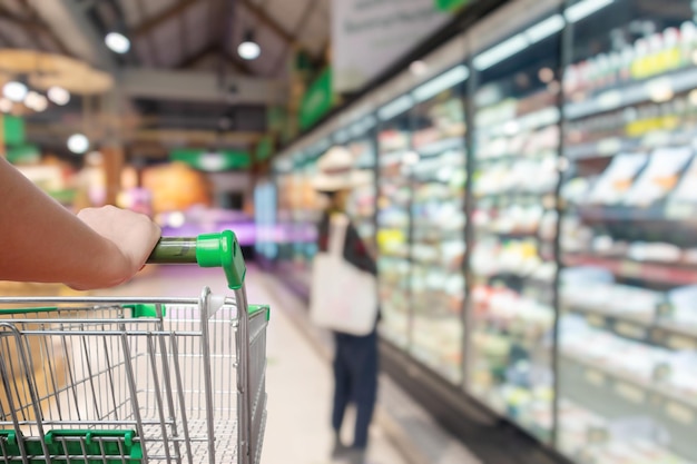 Femme poussant un chariot d'achat avec un arrière-plan flou de l'allée du supermarché