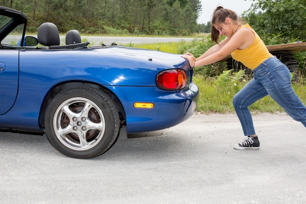 Femme pousse la voiture. A été cassé sur le côté