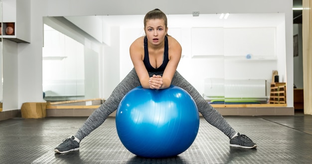 Femme pratiquant avec ballon de fitness dans la salle de sport