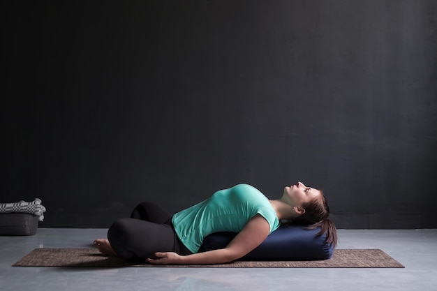 Femme pratiquant le concept de yoga couché dans l'exercice papillon incliné