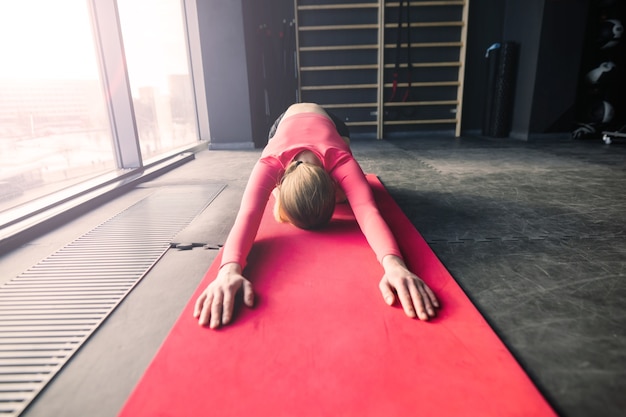 Femme pratiquant le yoga avancé sur tapis contre une grande fenêtre