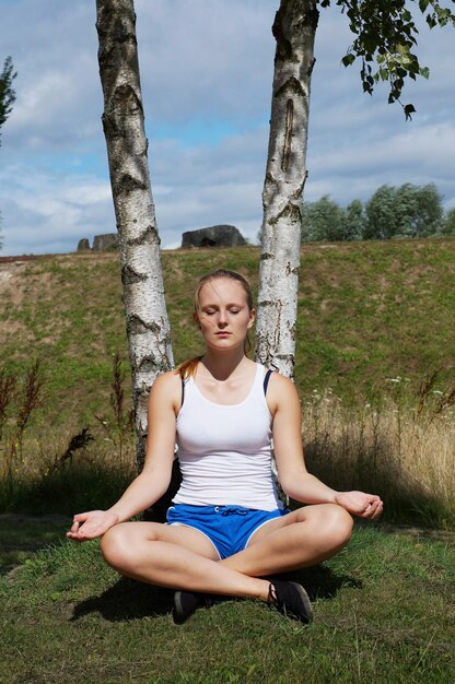 Photo une femme pratiquant le yoga dans un champ par une journée ensoleillée