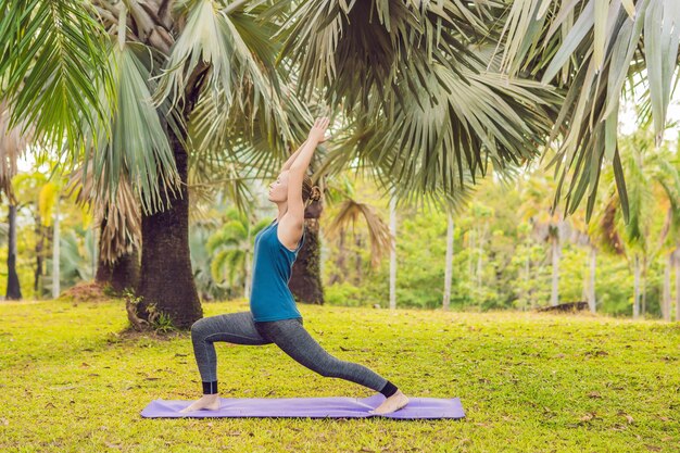 Femme pratiquant le yoga dans un parc tropical.