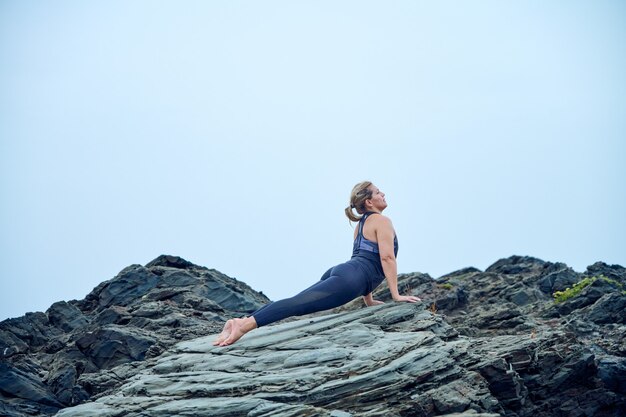 femme pratiquant le yoga devant la mer