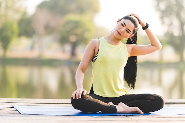 Femme pratiquant le yoga faisant du yoga dans le parc du matin