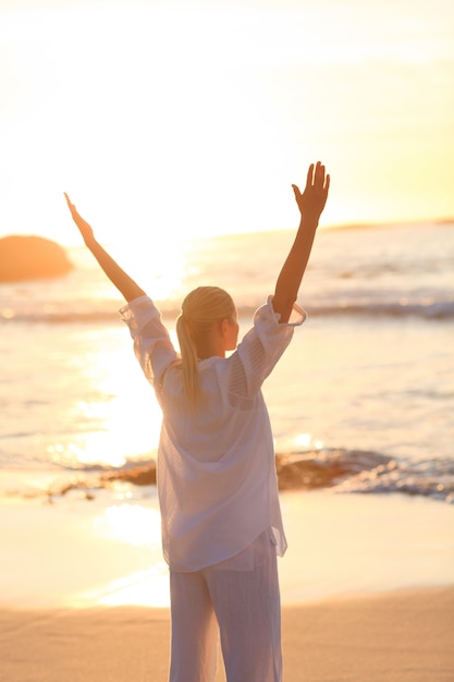 Femme pratiquant le yoga pendant le coucher du soleil