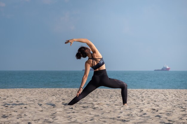 Une femme pratiquant le yoga sur la plage