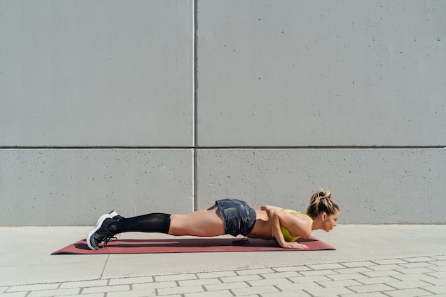 Femme pratiquant le yoga sur tapis à l'extérieur