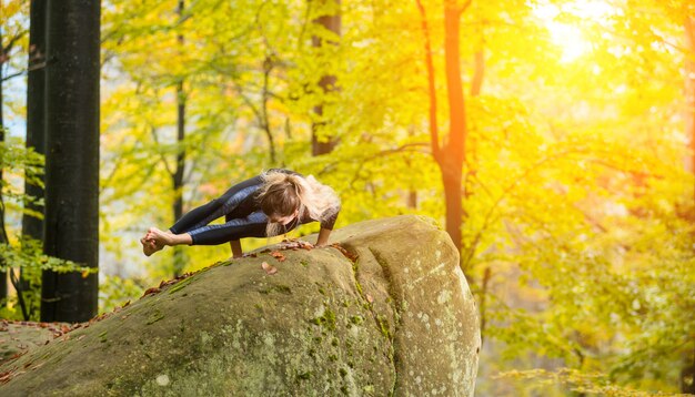 Femme pratique le yoga dans la forêt d&#39;automne sur la grosse pierre