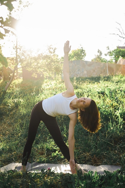 Photo femme pratique le yoga sur fond d'herbe verte dans le parc