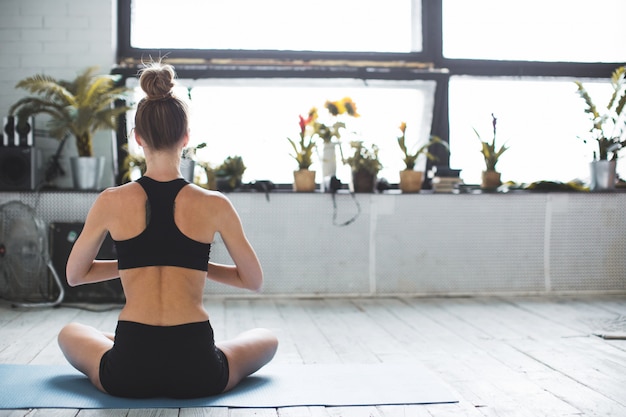 La femme pratique le yoga et médite à la maison.