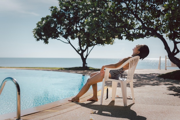 Photo femme prenant un bain de soleil près de la piscine en plein air en été