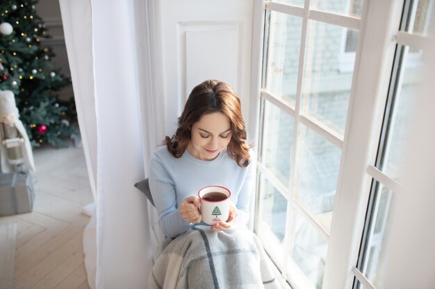 Femme prenant un café près de la fenêtre