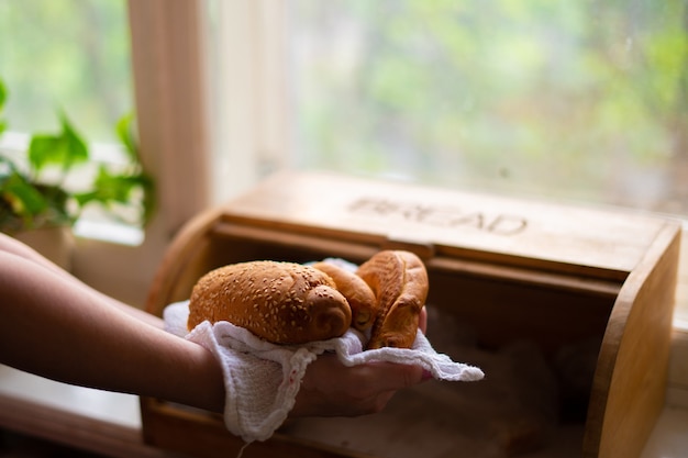 Femme prenant une miche de pain d'une boîte à pain dans la cuisine à la maison