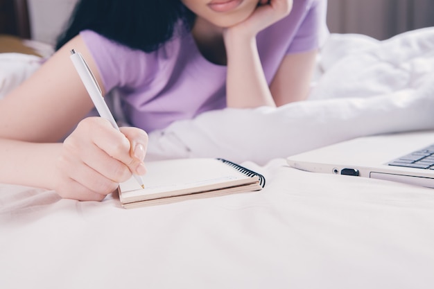 Femme prenant des notes sur un ordinateur portable