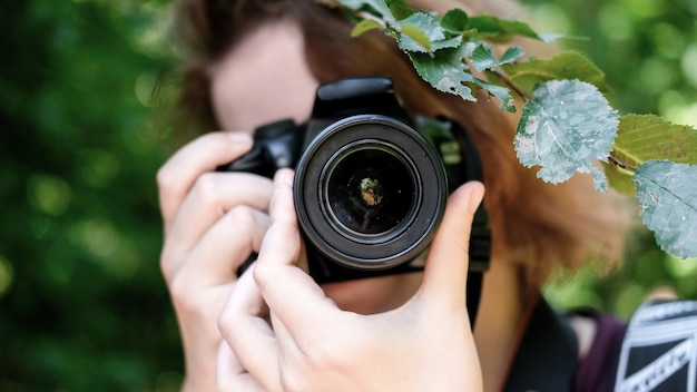 Femme prenant une photo d'une caméra principale à l'aide d'une caméra professionnelle. Verdure autour