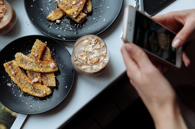 Femme prenant une photo du petit déjeuner avec les mains du smartphone tenir le téléphone d'en haut