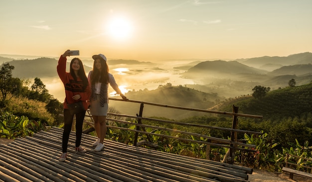 Femme prenant une photo avec un smartphone au sommet de la montagne