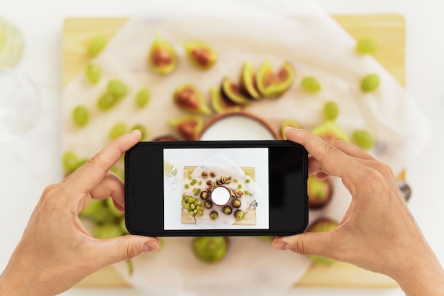 Femme prenant une photo de son délicieux yaourt grec aux figues par son smartphone