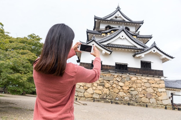Femme prenant une photo avec un téléphone portable sur le château de Hikone
