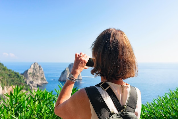 Femme prenant des photos de Faraglioni sur l'île de Capri, Italie