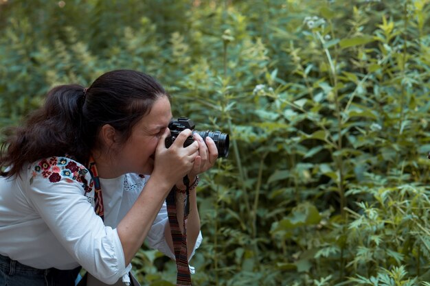 Femme prenant des photos de plantes sur un appareil photo professionnel Sony in park