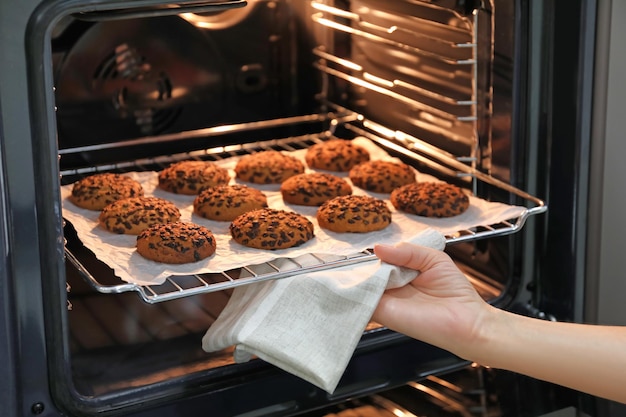 Femme prenant une plaque à pâtisserie avec de délicieux biscuits à l'avoine hors du four