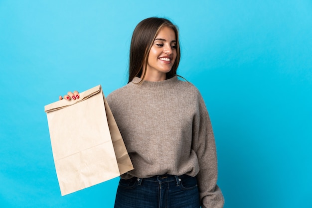 Photo femme prenant un sac de plats à emporter isolé sur bleu à côté