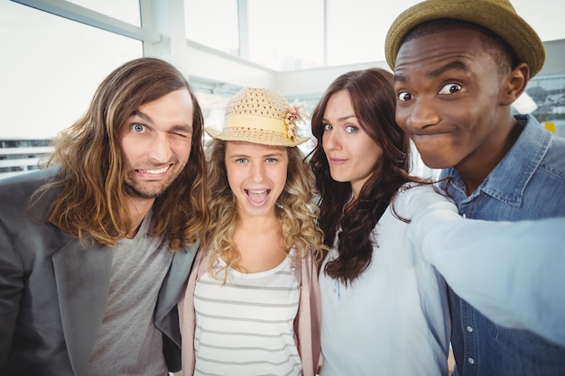 Femme prenant selfie avec des collègues de faire des visages