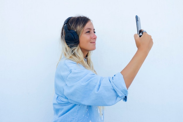 Femme prenant un selfie tout en écoutant de la musique au téléphone. fond blanc