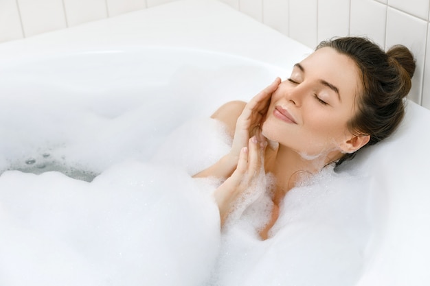 Femme prend un bain avec une mousse