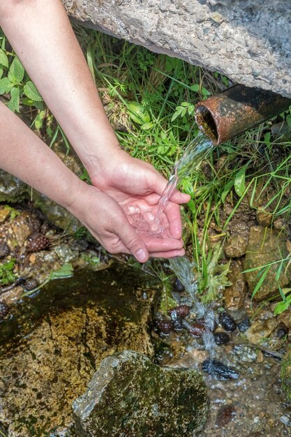 la femme prend de l'eau de source froide dans ses mains