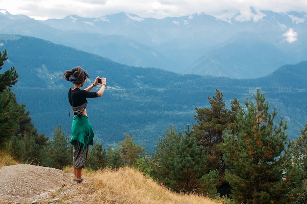 Femme prend une photo de montagnes