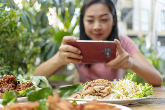 Femme prend une photo de la nourriture thaïlandaise sur la table.