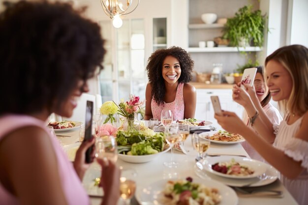 Une femme prend une photo de ses amies à un dîner.