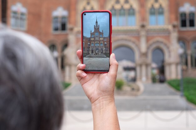 Une femme prend une photo avec un téléphone intelligent dans un bâtiment historique à Barcelone. Voyageur, tourisme, découverte, femme caucasienne