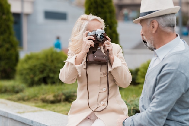 Femme prend des photos d'un vieil homme sur un appareil photo argentique vintage.