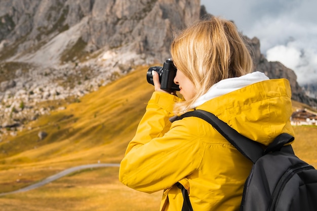 Une femme prend des photos d'un voyageur pittoresque du col passo giau avec un sac à dos utilise un appareil photo pour capturer un italien