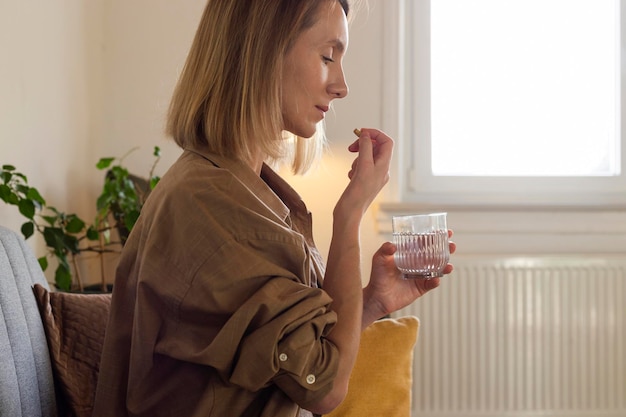 Une femme prend des pilules de vitamines à la maison