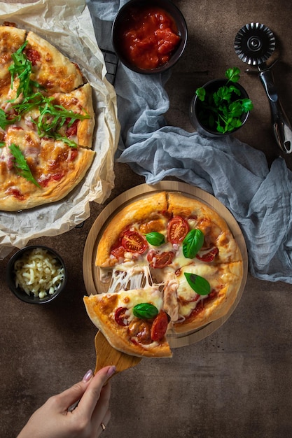 Une femme prend une tranche de pizza à la tomate et au bacon qui est sur la table