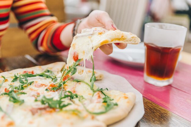 Femme prendre un morceau de pizza gros plan soft focus