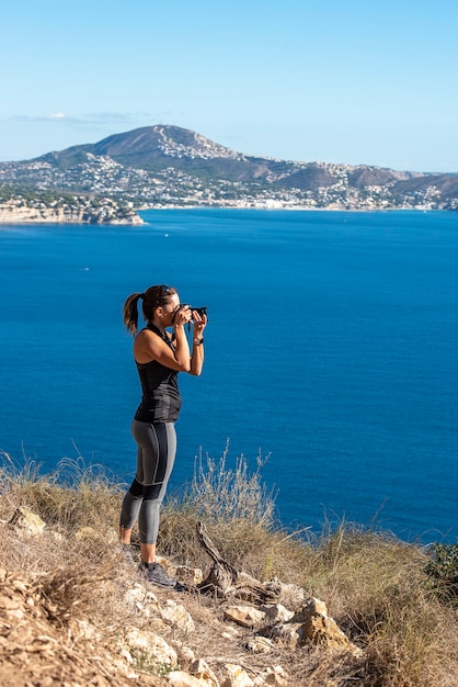 Femme à prendre des photos avec son appareil photo pour le paysage, dans la nature du Peñon de Ifach à Calpe