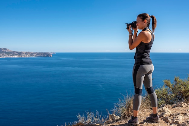 Femme à prendre des photos avec son appareil photo pour le paysage, dans la nature du Peñon de Ifach à Calpe