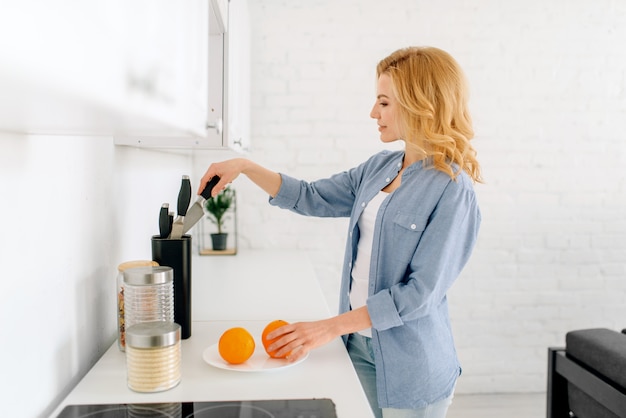 Femme préparant des oranges, petit-déjeuner dans la cuisine