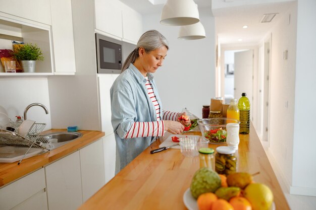 Femme préparant le poivre pour la salade dans la cuisine