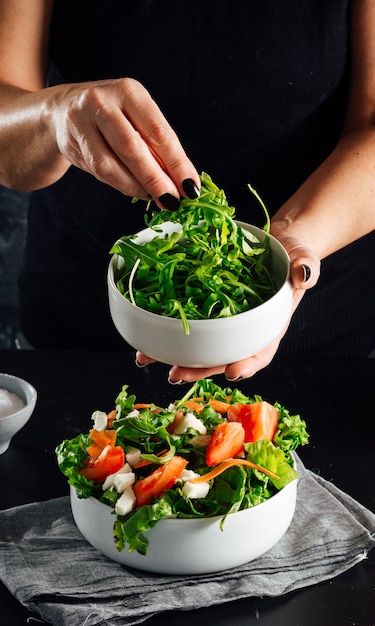 Femme préparant une salade aux tomates laitue huile d'olive et sel Concept d'une alimentation saine