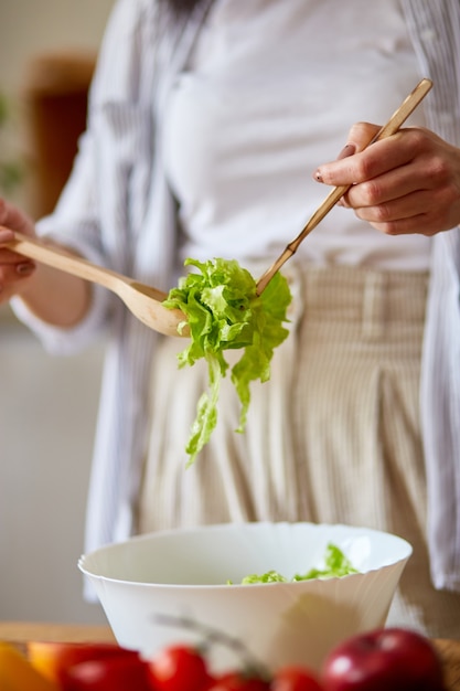 Femme préparant une salade de légumes dans la cuisine