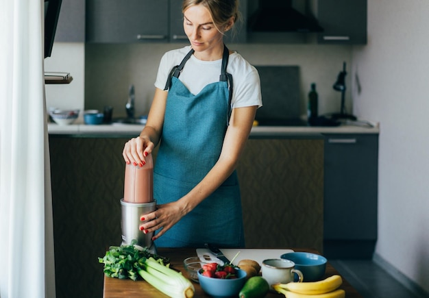 Femme préparant un smoothie dans la cuisine