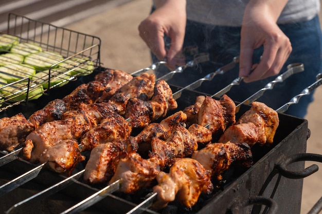 Femme préparant de la viande sur des brochettes et des légumes sur le gril dans l'arrière-cour